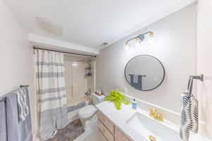Full bath featuring vanity, shower / tub combo, and a textured ceiling