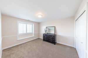 Unfurnished bedroom with light carpet and a closet