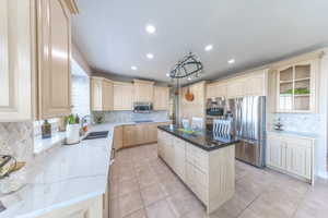 Kitchen with light wood finish cabinets, stainless steel appliances, backsplash, quartz countertops, and recessed lighting