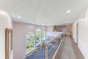 Corridor featuring an upstairs landing, recessed lighting, a textured ceiling, and carpet floors