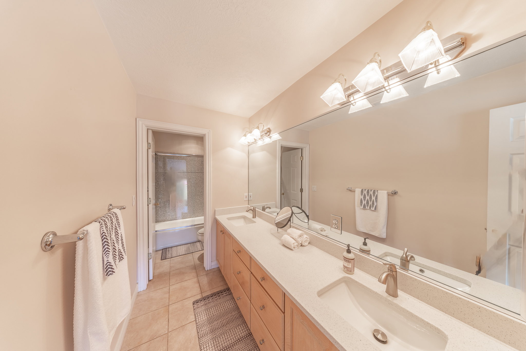 Bathroom featuring double vanity, light tile patterned floors, and shower / bath combo