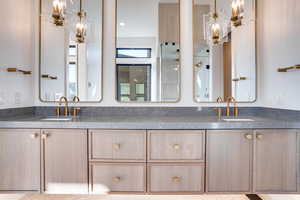 Bathroom featuring double vanity, a chandelier, and a shower