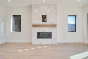 Unfurnished living room with light wood finished floors, recessed lighting, and a tile fireplace