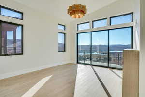 Empty room featuring a mountain view, light wood-type flooring, vaulted ceiling, and a chandelier