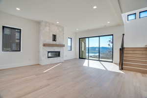 Unfurnished living room featuring a mountain view, light wood finished floors, a fireplace, and recessed lighting