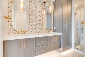 Bathroom with double vanity, a stall shower, and backsplash