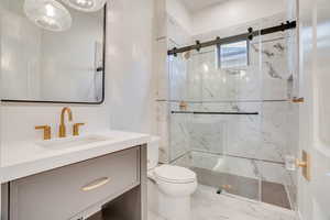 Full bath featuring vanity and a marble finish shower