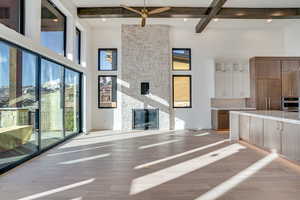 Unfurnished living room featuring a fireplace, light wood-type flooring, and a ceiling fan