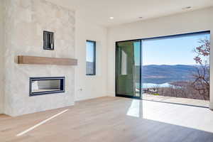 Unfurnished living room featuring a mountain view, a tile fireplace, light wood-type flooring, and recessed lighting
