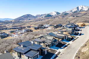 Aerial view of property and surrounding area featuring mountains and nearby suburban area