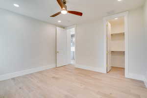 Unfurnished bedroom featuring light wood-type flooring, a spacious closet, recessed lighting, and ceiling fan