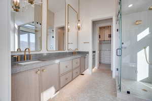 Full bath with double vanity, a stall shower, a spacious closet, and parquet floors