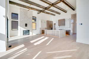 Unfurnished living room with light wood-style flooring, a ceiling fan, a stone fireplace, and recessed lighting