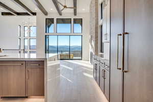 Kitchen with a mountain view, light stone counters, light wood-type flooring, a ceiling fan, and a chandelier