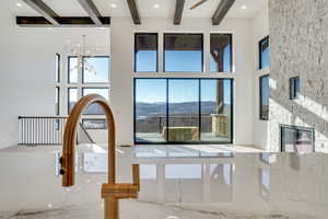 Kitchen view of a stone fireplace, hanging lights, beamed ceiling, and light stone counters
