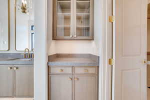 Bar area with light countertops, glass insert cabinets, and light wood finish cabinetry