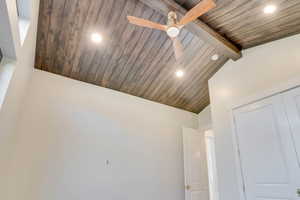 Detailed view of recessed lighting, a ceiling fan, and a wood ceiling with exposed beams