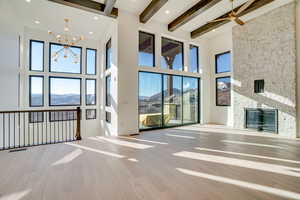 Unfurnished living room with a mountain view, a stone fireplace, light wood-style flooring, suspended lighting, and a ceiling fan