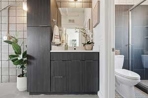 Bathroom with vanity, a stall shower, and tile walls