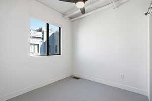 Unfurnished room with a ceiling fan and finished concrete flooring