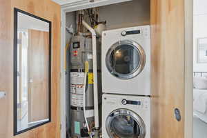 Laundry area with stacked washer / dryer and strapped water heater