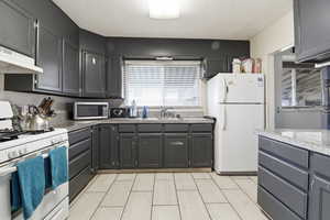 Kitchen featuring white appliances, gray cabinets, and light countertops