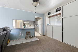 Kitchen with a kitchen bar, gray cabinetry, a peninsula, light countertops, and light colored carpet