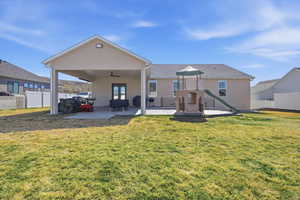 Back of house featuring a ceiling fan, a patio area, a playground, and stucco siding