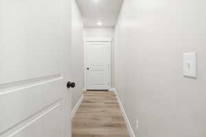 Corridor featuring light wood-style flooring and baseboards