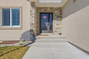 Doorway to property featuring stone siding and stucco siding