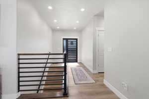 Hallway with light wood-style floors and recessed lighting