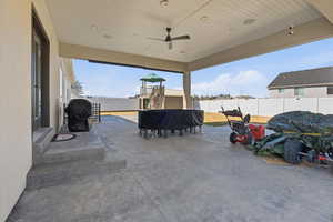 Fenced backyard with a patio, area for grilling, and a ceiling fan