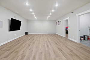 Unfurnished living room featuring baseboards and light wood-style flooring