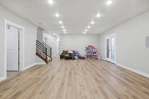 Recreation room with light wood-style flooring and recessed lighting