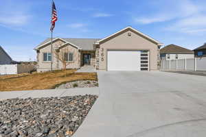 Single story home featuring a garage, concrete driveway, stucco siding, and stone siding