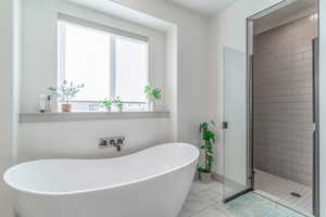 Bathroom featuring a shower stall, a freestanding bath, and light marble finish floors