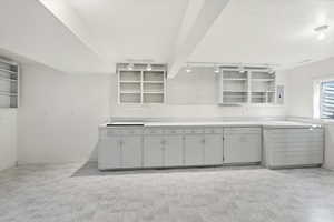 Studio or shop area or change into a bedroom with light countertops, track lighting, open shelves, and electric panel