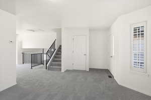 Carpeted spare room with stairs and baseboards