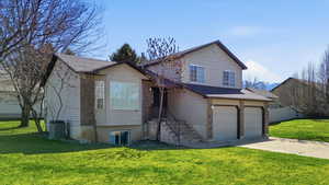View of front of home with a front lawn, concrete driveway, an attached garage, and a shingled roof