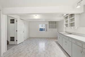 Studio with open shelves, light countertops, rail lighting, and white cabinets