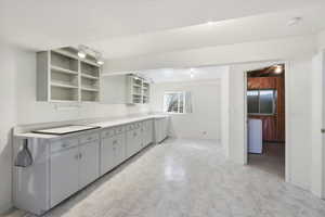 Studio with light countertops, open shelves, rail lighting, light floors, and washer / dryer