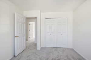 Unfurnished bedroom featuring light colored carpet and a closet