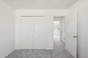 Unfurnished bedroom featuring light colored carpet and a closet