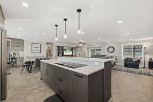 Kitchen featuring open floor plan, crown molding, freestanding refrigerator, a ceiling fan, and a center island