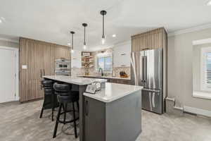 Kitchen featuring two tone color scheme, stainless steel appliances, crown molding, a kitchen bar, and open shelves