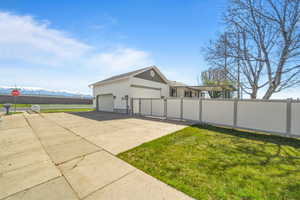 View of property exterior with a gate, concrete driveway, an attached garage, and a mountain view