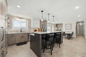 Kitchen featuring a kitchen bar, dual tone cabinetry, backsplash, a kitchen island, and stainless steel appliances