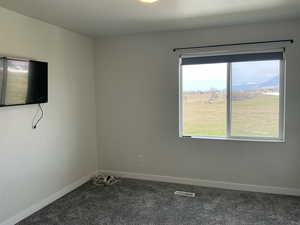 Empty room with dark carpet, a mountain view, and a textured ceiling