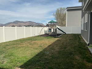 Fenced backyard featuring a playground and a mountain view