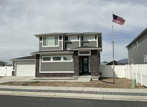 Prairie-style house with a gate, stone siding, concrete driveway, and an attached garage